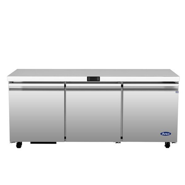 A large, stainless steel Atosa AUR72SD undercounter refrigerator features three doors, a flat top surface, small black wheels, and a digital control panel above the center door. The Ava brand logo is on the lower right corner.