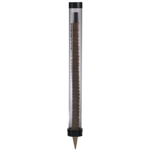 A transparent cylindrical tube with black caps at both ends contains a vertical stack of brown hexagonal pencils, gravity fed through the tube. The bottom cap forms a conical point like a pencil tip. The tube stands upright against a white background.