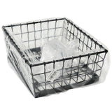 A black powder coated Transformer Basket, square-shaped and partially covered with a clear plastic bag, features a barcode sticker on the bottom. The photo is taken against a plain white background, resembling a sturdy food pan holder.