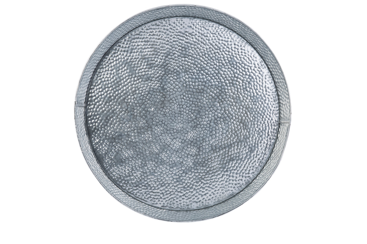 A round, metallic TableCraft tray with a raised, hammered texture and slight lip around the edge. Crafted from galvanized steel, its surface features small, uneven indentations for a reflective, patterned look. The background is plain white.