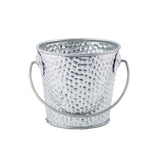 A small, round, silver galvanized pail with a textured, hammered surface and a curved handle attached at two sides. The bucket is empty and placed against a plain white background.
