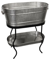 From the Brickhouse Collection by TableCraft Products, this Beverage Tub Set features a large, oval hammered metal tub with handles on a sturdy black stand. Below, a matching textured tray sits on the lower shelf for added style and function.