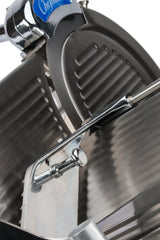 Close-up of a compact slicer from the Chefmate Series, featuring a circular serrated blade and adjustable thickness lever. Grooved surface and stainless steel construction shine under light. A blue label with partial text appears at the top.