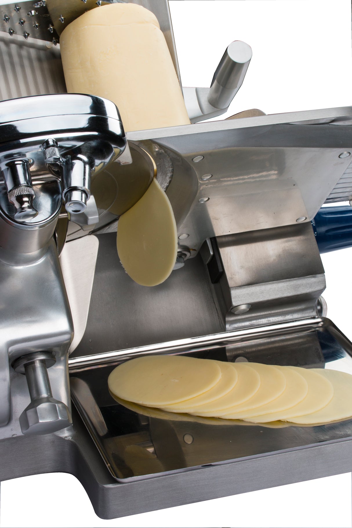 A cylindrical block of cheese is being sliced by a compact Chefmate Series deli slicer. Thin, oval slices fall onto a metal tray below the blade. The shiny 12 inch slicer is shown against a white background.