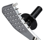 Close-up of a metal meat tenderizer with a textured, diamond-shaped surface and short metal spikes, positioned beside a manual slicer. It features a white plastic peg, black cylindrical handle, and round guard against a plain white background.