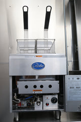 A commercial stainless steel fryer with two metal baskets rests inside. The silver gas countertop fryer features a “Globe” logo, control knobs, a warning label, and visible gas and electrical components. It offers a 30-lbs fat capacity. Background is stainless steel.
