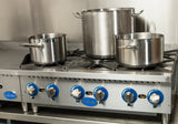 A commercial stainless steel Globe GHP36G gas countertop hotplate with three large burners, each holding a shiny metal pot of varying sizes. The stove features blue control knobs labeled “Globe,” and a metallic backsplash in the background.