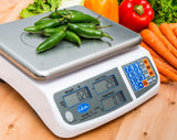 A price computing scale displays 0.26 pounds of green chili peppers at $2.99 per pound, totaling $0.78. Fresh vegetables including lettuce, bell peppers, and carrots rest on a wooden surface in the background.