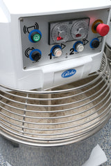 A close-up of a Globe spiral dough mixer with control knobs, buttons, and dials on the front panel. The stainless steel bowl below holds 130 lbs capacity of dough, protected by a wire safety guard.