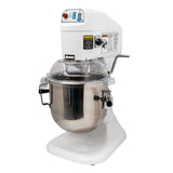 A large commercial planetary mixer with a white base, digital control panel, stainless steel mixing bowl, and clear plastic safety guard. Warning and caution labels are attached to the front and side of this countertop mixer.