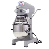 A large commercial planetary mixer with a stainless steel mixing bowl, protective wire guard, control panel, lever on the side, and a black power cord—all in a gray metal body—designed for heavy-duty food preparation as a dependable 20 qt mixer.