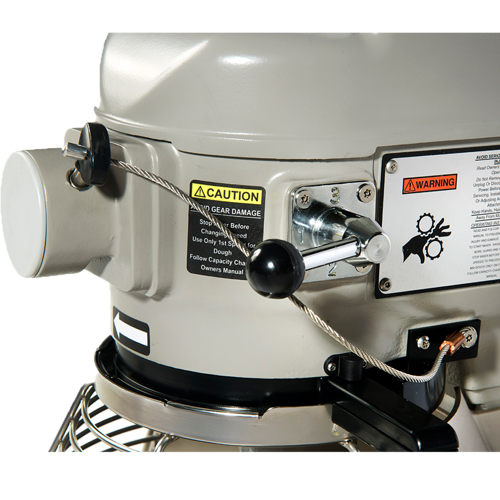 Close-up of a Globe Middleby machine with a silver-gray metal body, warning labels, black control lever, and safety cable. Labels include yellow “CAUTION,” red “WARNING” signs with instructions, and a gear diagram from the Correctional Package XXCORR-20.