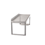 A stainless steel tabletop grill with a rectangular frame and parallel grill bars, elevated on sturdy legs. Featuring a removable wire rack, the open design has clean, modern lines and a minimalist look, set against a plain white background.