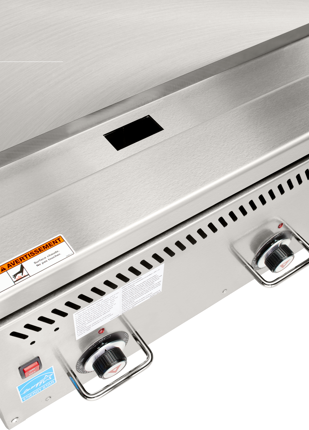 Close-up of a stainless steel Heavy Duty Griddle, featuring two control knobs, a red power switch, ventilation slots, and warning labels. The chrome plate cooking surface is clean, with a modern and industrial design.