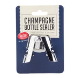 A silver stainless steel and silicone Champagne bottle sealer, which is dishwasher safe, is attached to blue and white packaging labeled “Champagne Bottle Sealer.” The “TableCraft” logo appears on the left, framed by a decorative border.
