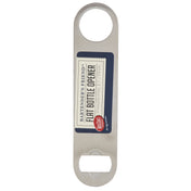 A stainless steel flat bottle opener with a circular hole at one end and a bottle-opening slot at the other. This pocket bottle opener is dishwasher safe, with a navy label reading “Bartender’s Friend™ Flat Bottle Opener, Stainless Steel, 7 1/8 in., TableCraft.”.