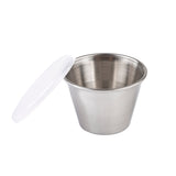 A small TableCraft stainless steel ramekin is shown with a white plastic lid resting beside it. The 2-1/2 oz ramekin has a brushed metal finish and a wide opening, with both items set against a plain white background.