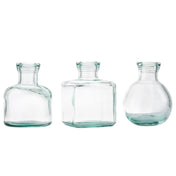 Three clear recycled glass bottles with short necks and wide mouths stand side by side. These versatile vases—cylindrical, square, and round—are empty, transparent, and set against a plain white background.