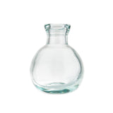 A clear, round-bottomed glass bottle with a short, wide neck and a slightly flared rim. Made from recycled glass, it is smooth, transparent with a subtle bluish tint. The empty bottle is photographed against a plain white background.