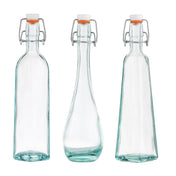 Three empty TableCraft resealable bottles with metal swing-top lids and orange rubber seals, each uniquely shaped—square, rounded with a tapered middle, and rectangular. Made from transparent recycled glass, all stand upright on a white background.