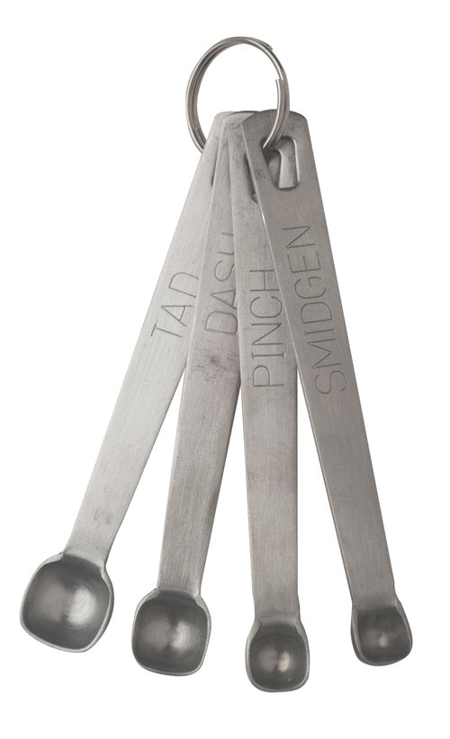 A set of four metal measuring spoons on a keyring labeled “TAD,” “DASH,” “PINCH,” and “SMIDGEN” fanned out beside a J.A. Henckels Steel sharpening steel, perfect for precise ingredient measurements and maintaining sharp blades.