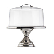 A shiny stainless steel cake stand with a wide base and a tall, clear cake stand cover featuring a small black handle on top. The empty stand and cover are set against a plain white background.
