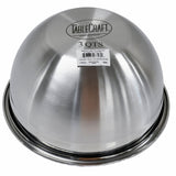 A shiny, metallic stainless steel mixing bowl from TableCraft is upside down, revealing its round bottom. The label, brand name, and barcode sticker are visible on the base of this premium mixing bowl against a plain white background.