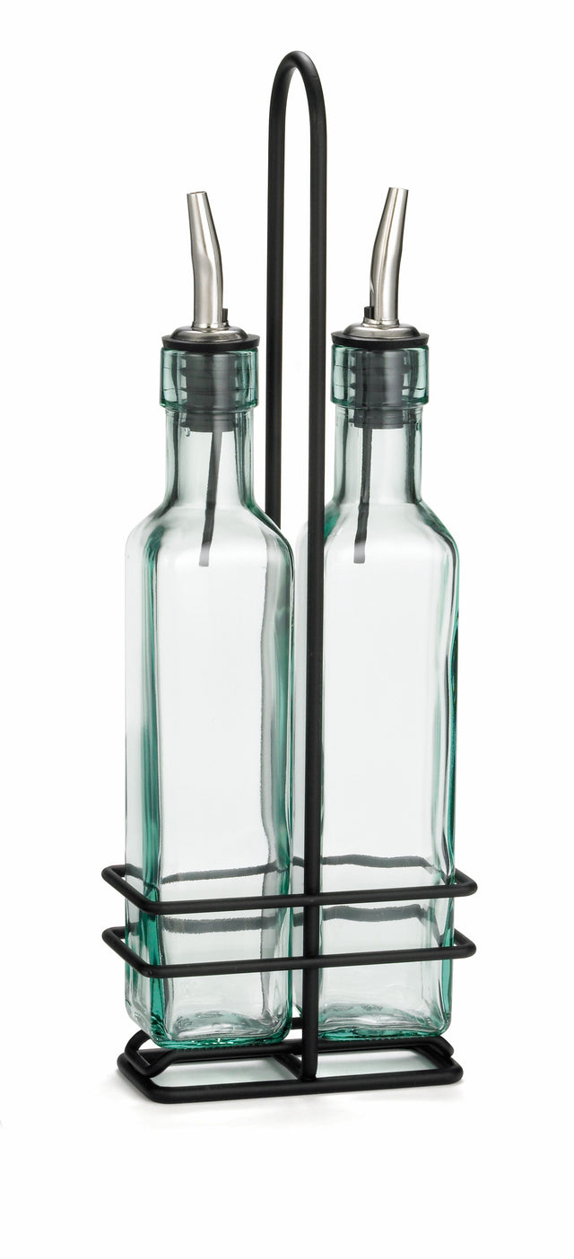 Two clear glass bottles with stainless steel pourers sit side by side in a sturdy metal rack with a handle. Perfect for dispensing oil and vinegar, these bottles add elegance to any kitchen. The minimalist design stands out against the white background.