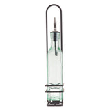 A clear green tint glass bottle with a stainless steel pourer sits in a tall, black metal holder with a handle and three horizontal rings securing the bottle upright. The design is minimalist and functional.