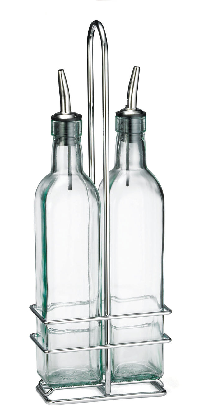 Two clear glass bottles with stainless steel pourers sit side by side in a chrome plated rack with a tall handle, against a white background. The rectangular bottles have rounded shoulders and long necks, making an elegant glass bottle set for your table.