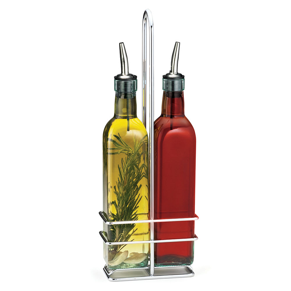 Two glass bottles with stainless steel pourers are held in a chrome plated rack. One contains yellow oil with rosemary, the other red vinegar. The stylish caddy features a tall central handle for easy carrying—an elegant glass bottle set for your table.