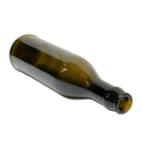 A dark green glass bottle lies on its side on a white background. The empty bottle, with a stainless steel pourer attached to its narrow neck, has a wide body and no visible labels or markings.