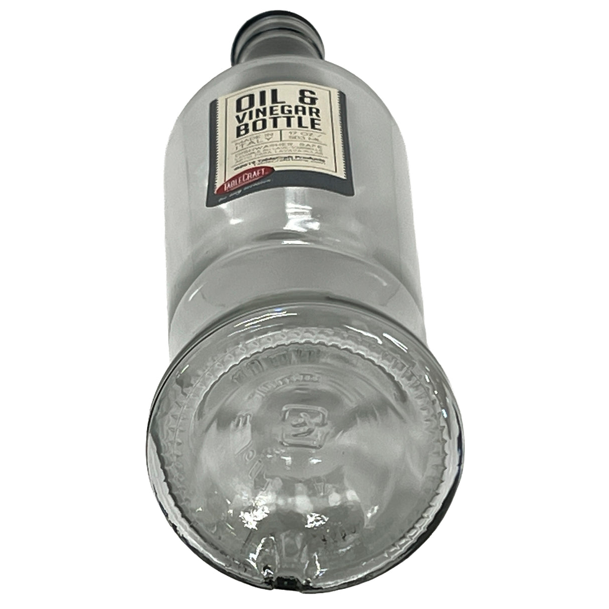 A clear Sottile Glass Bottle, 17 oz, stands upright with a label reading “Oil & Vinegar Bottle.” Viewed from the bottom, the round base and embossed markings are visible. The bottle is paired with a stainless steel pourer for easy dispensing.
