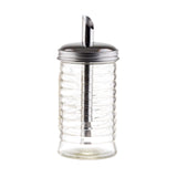A clear ribbed glass sugar pourer from the Beehive Collection features a stainless steel pour spout and metal lid, perfect for precise pouring; the empty container is photographed on a white background.