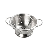 A shiny stainless steel mini colander with two handles, a wide base, and evenly spaced round holes for draining water from food sits on a white background.