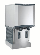 A modern, stainless steel ice and water dispenser with Touchfree infrared dispensing and two black nozzles for nugget ice and water. The Scotsman brand is displayed on the top panel, complementing its boxy shape and sleek, industrial design.