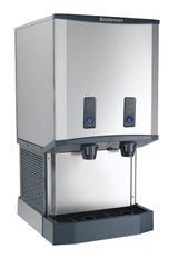 A stainless steel Meridian ice and water dispenser with two black dispensing nozzles, labeled buttons for ice and water, a drip tray below, and a modern, boxy design suitable for commercial or office use.