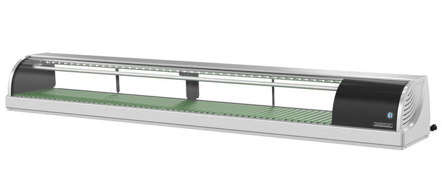 A long, stainless steel Hoshizaki refrigerated sushi case with a curved glass front, green slatted base, and built-in LED lighting. The unit has black end panels and an adjustable vent on the right side for showcasing fresh sushi.