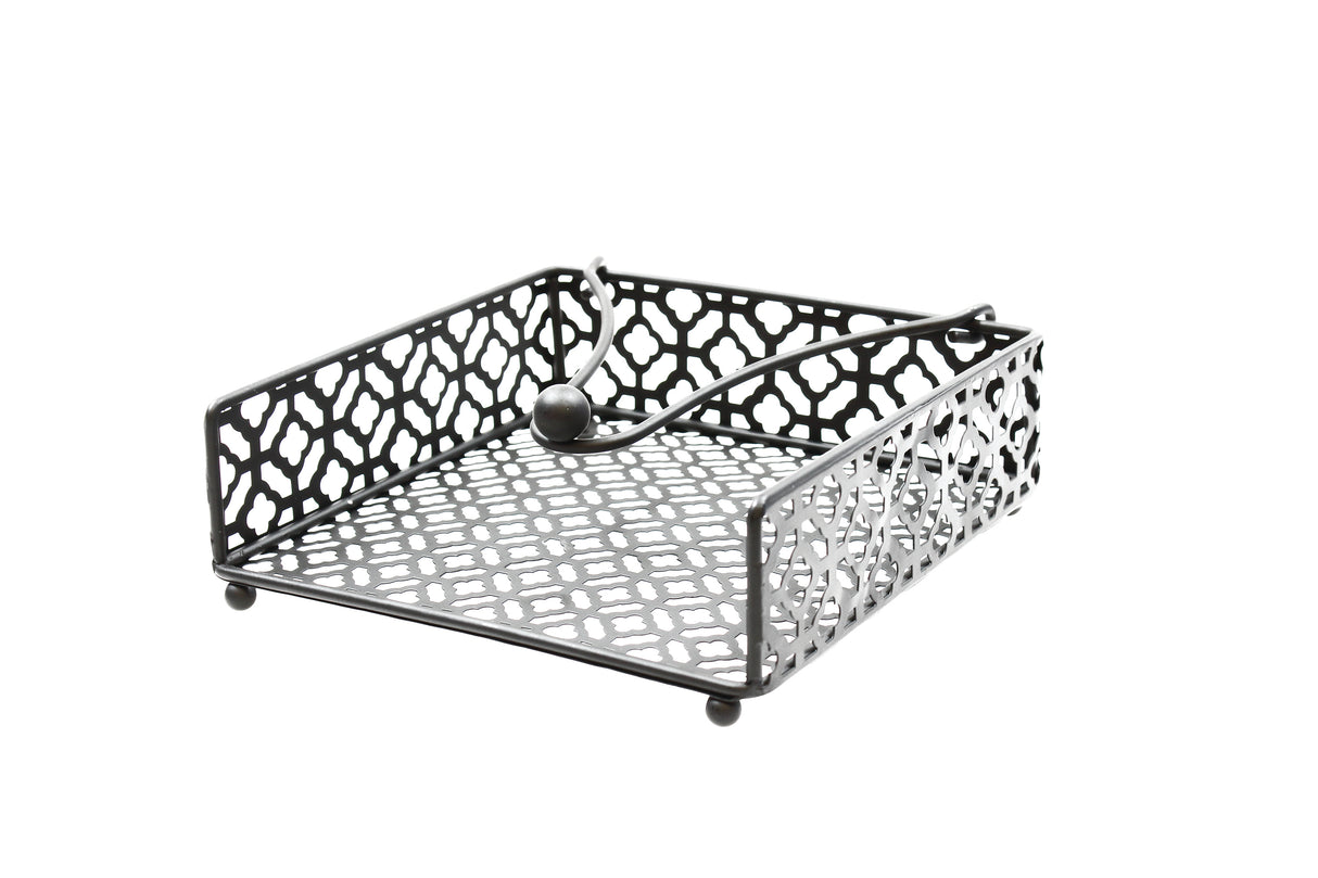 A black powder coated metal napkin holder from the TableCraft Farmhouse Collection features a geometric cut-out pattern, four round feet, and a weighted arm with a ball end to keep napkins in place. Photographed on a white background.