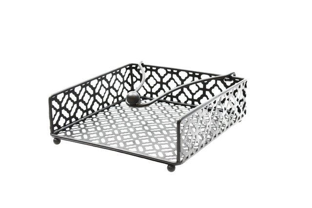 A black powder coated metal napkin holder from the TableCraft Farmhouse Collection features a geometric cut-out pattern, four round feet, and a weighted arm with a ball end to keep napkins in place. Photographed on a white background.