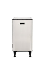 A stainless steel, box-shaped appliance with a front-facing slot, a hinged door on the left side, four black adjustable legs, and an interior storage shelf, photographed against a plain white background.