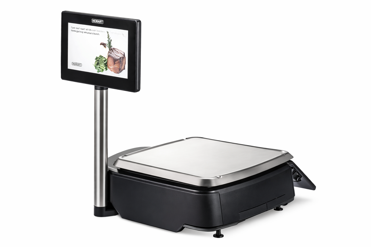 A digital retail scale with a flat stainless steel weighing platform, HTi scale printer with Auto Cutter, and a black base. A vertical pole supports a display screen showing meat and vegetables. The device is set against a plain white background.