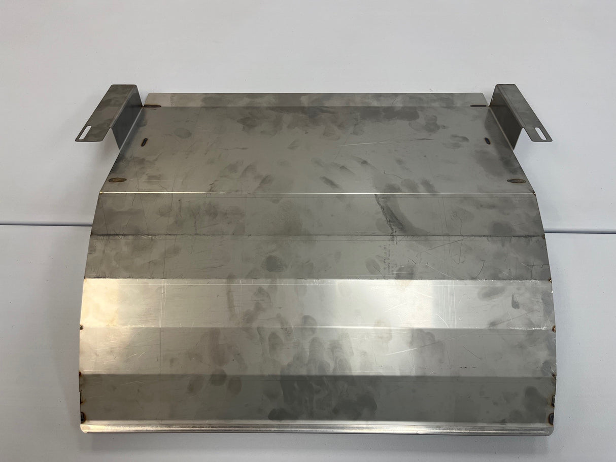 A rectangular bin deflector with a slightly curved, brushed metal surface and visible weld marks. Two metal brackets extend upward from the back corners. This Icetro America piece rests on a plain, light-colored surface.