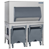 A large commercial top-mounted ice maker with a stainless steel exterior, gray front door, and two gray rolling ice storage bins beneath it. The unit features the Ice Express Transport System and Scotsman branding in the top right corner.