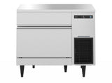 A Hoshizaki undercounter ice maker with a flat top, digital control panel, and lower right ventilation grille. This cube-style ice maker stands on black legs, features a left-side ice retrieval door, and boasts a clean, reflective stainless steel surface.