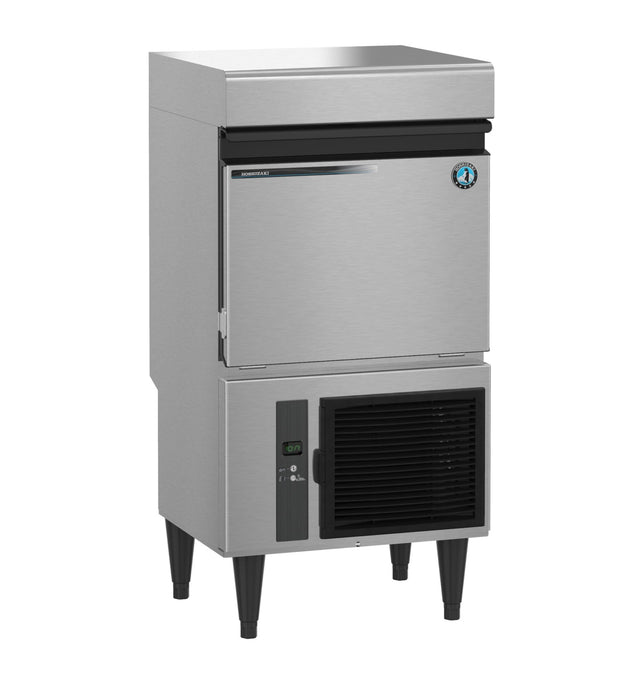 A Hoshizaki commercial stainless steel Specialty Cube-Style Ice Maker with a top ice bin, drop-down front door, lower ventilation panel with power switch, four black legs, and a blue and white circular badge on the upper right door.