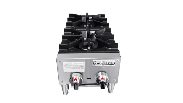 A stainless steel Connerton countertop gas stove with 2 burners, each controlled by a red-marked knob. Lighting instructions are on the front, and the stove stands on four metal legs against a white background.