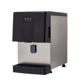 A modern countertop ice & water dispenser with a stainless steel body and black top. It features a front tap, a drip tray at the bottom, and touch control buttons on the upper front panel. The background is plain white.