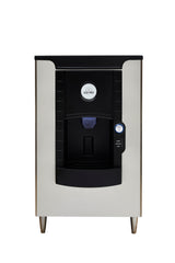 A front view of an Icetro America ice dispenser, a stainless steel and black automatic hotel ice dispenser with a digital display and dispensing area in the center, standing on four short metal legs against a white background.