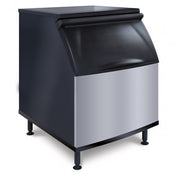 A commercial NSF ice storage bin with a stainless steel front panel, black plastic top, and sturdy black legs. The sloped lid allows easy access, making it perfect for use with an ice maker in restaurants or food service settings. Plain white background.